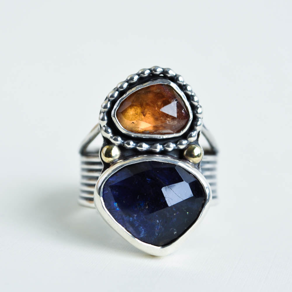 A deep midnight purple iolte gemstone paired with a golden brown tourmaline. Set in sterling silver with a split ridged band.