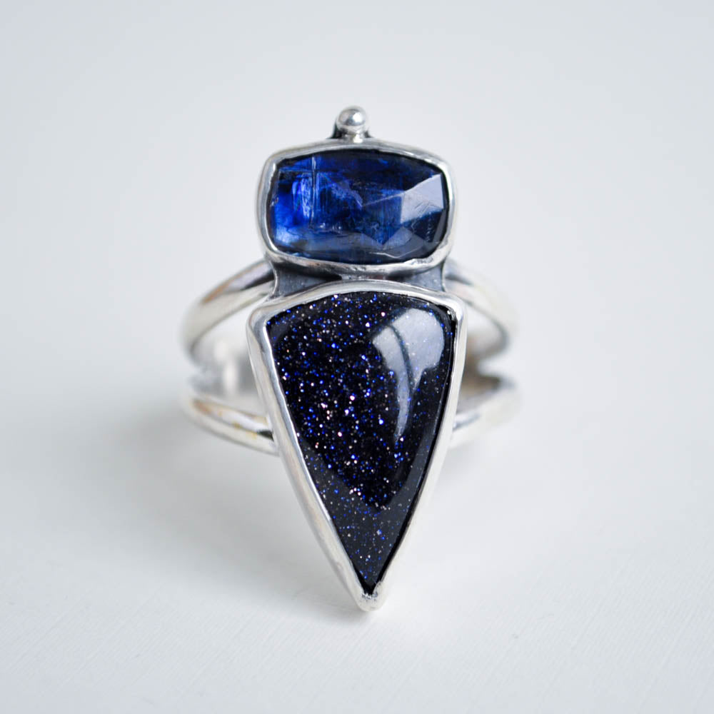 Sterling silver statement ring featuring a shield shaped navy blue goldstone gemstone and a blue kyanite on a split band.