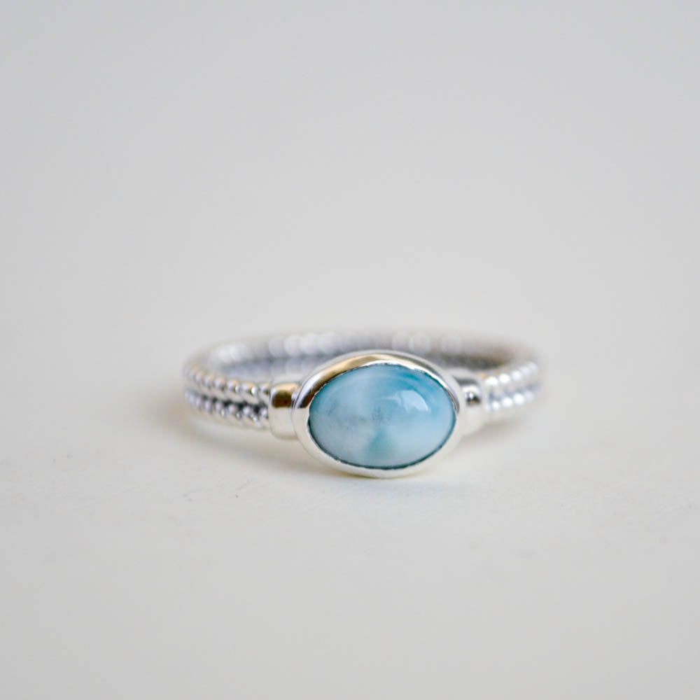 Larimar oval gemstone bezel set horizontally on a double twist sterling silver ring band.