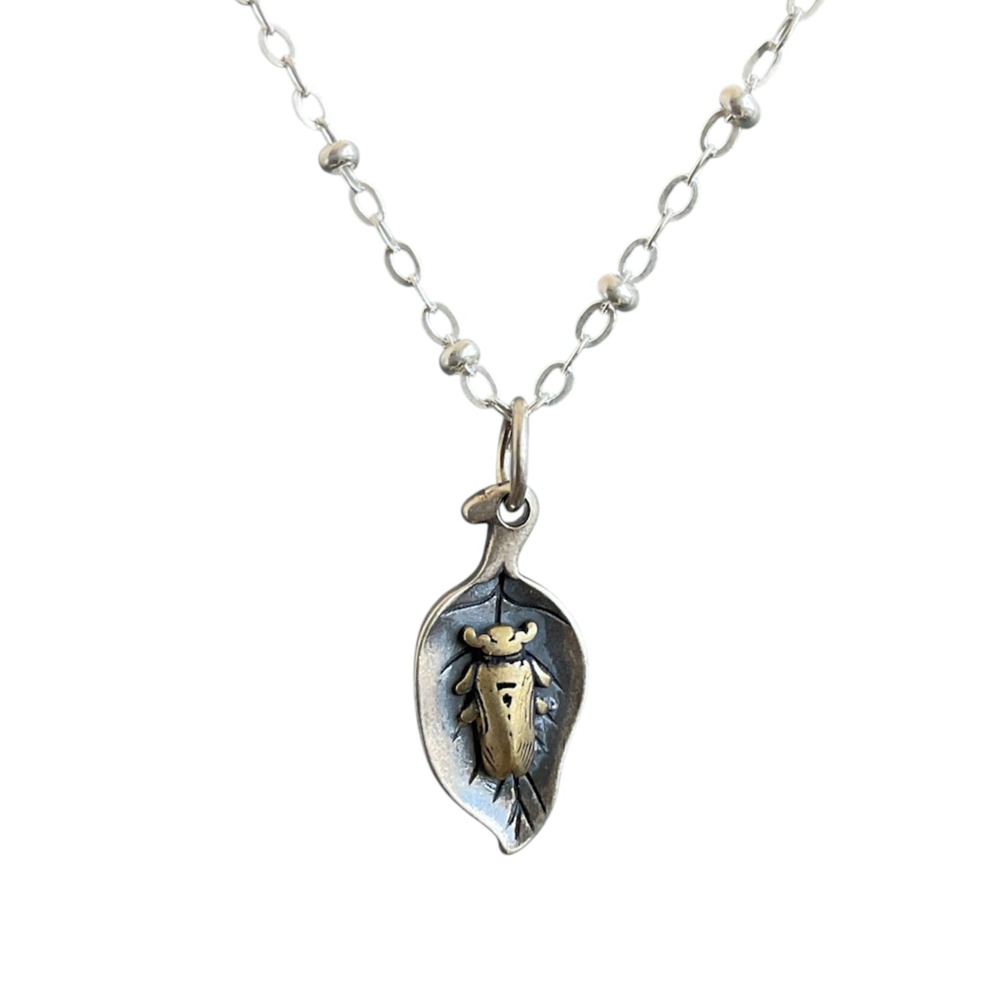 Brass beetle sleeping on a sterling silver leaf, on a satellite chain.