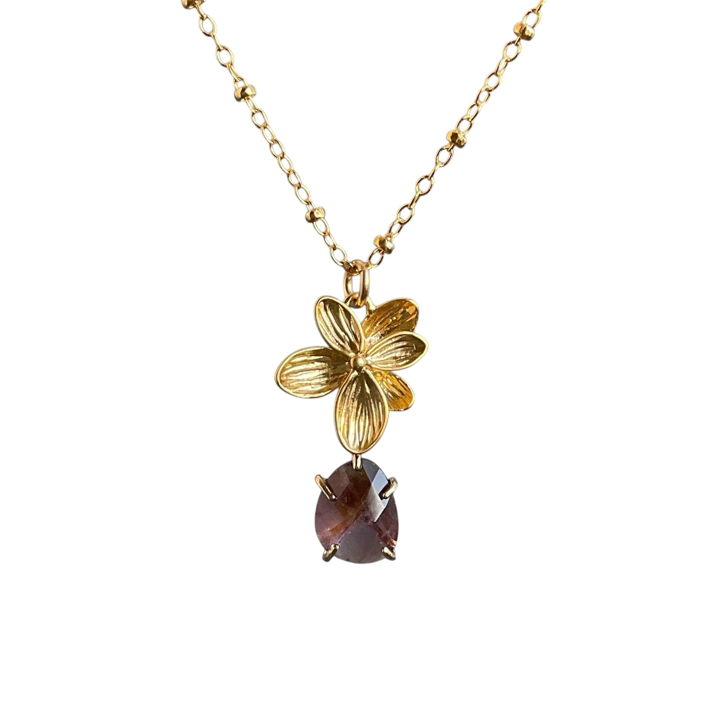 Gold orchid pendant with a purple drop underneath on a gold chain.