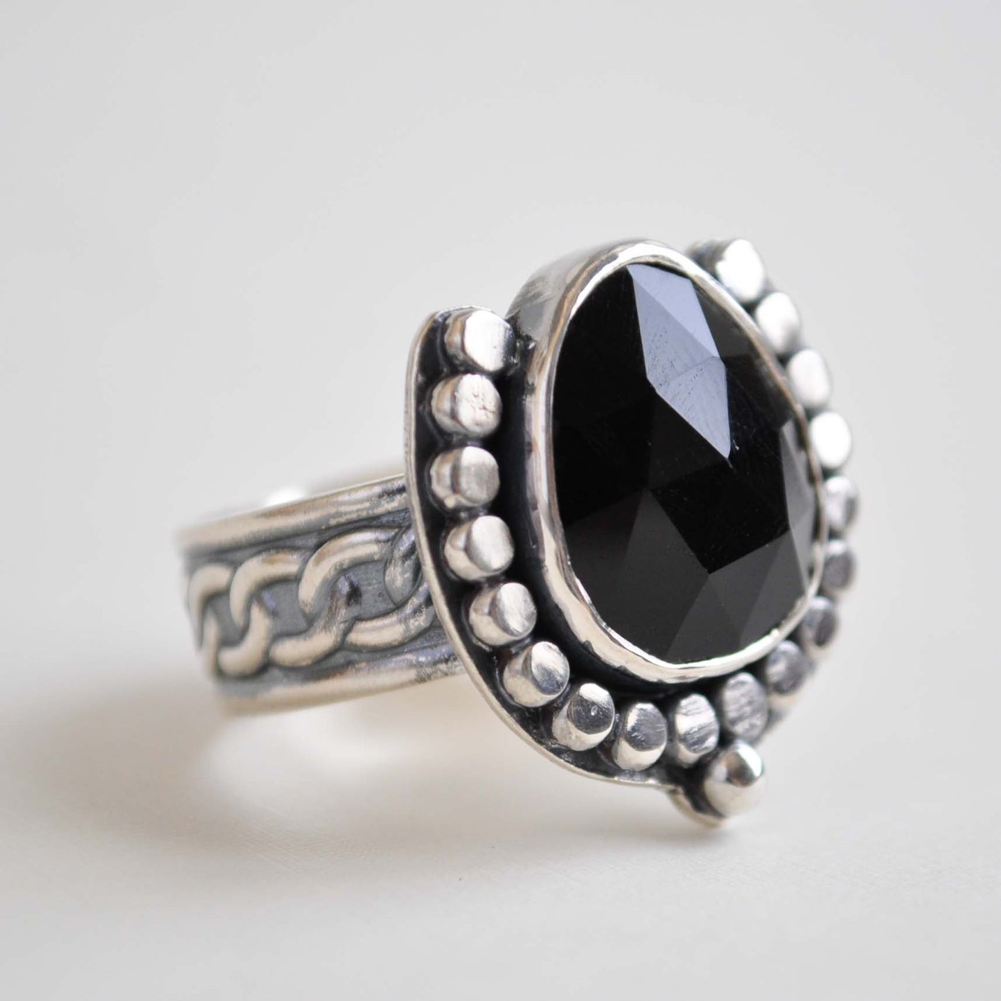 Silver ring with a black gemstone on a light gray background