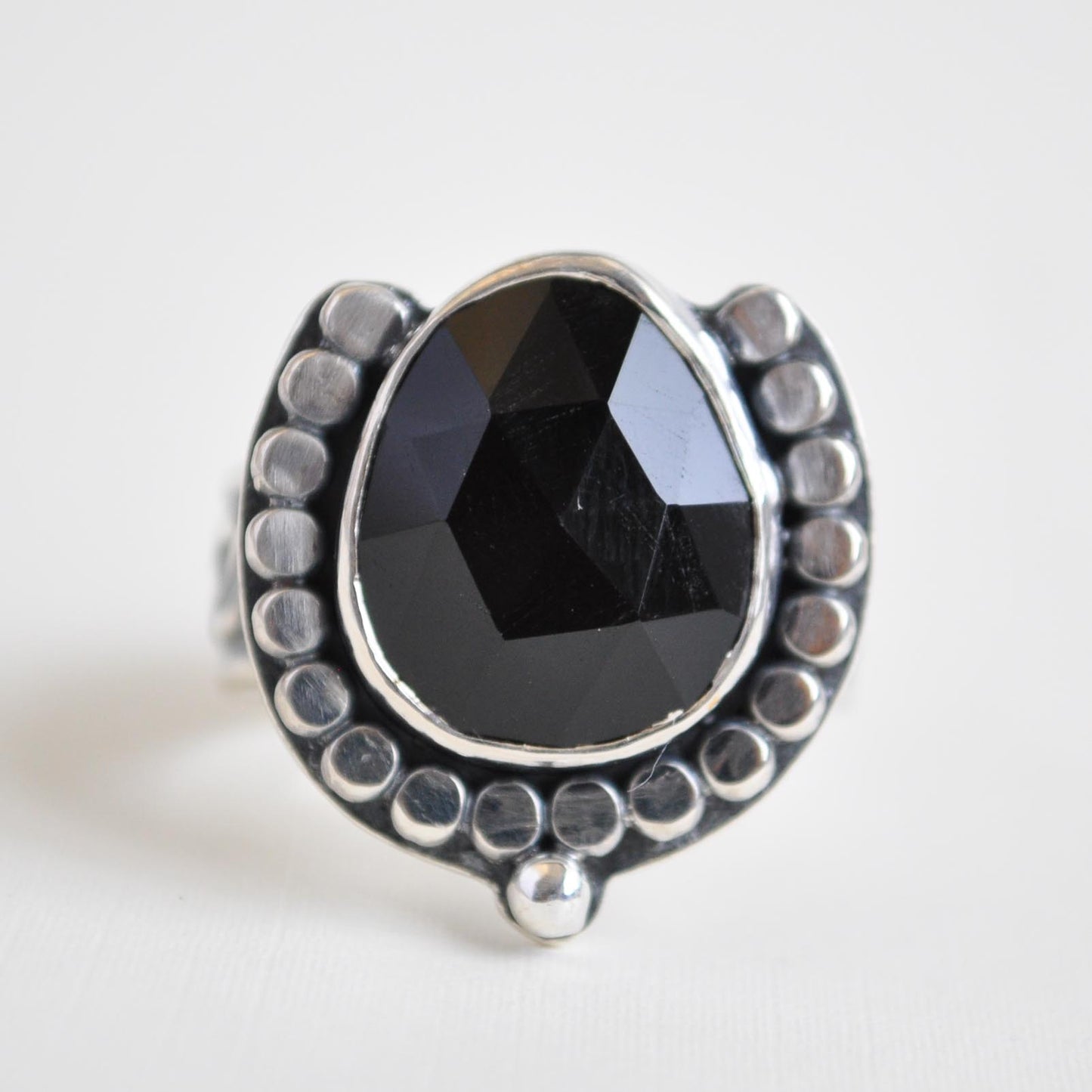 Silver ring with a black gemstone on a light gray background