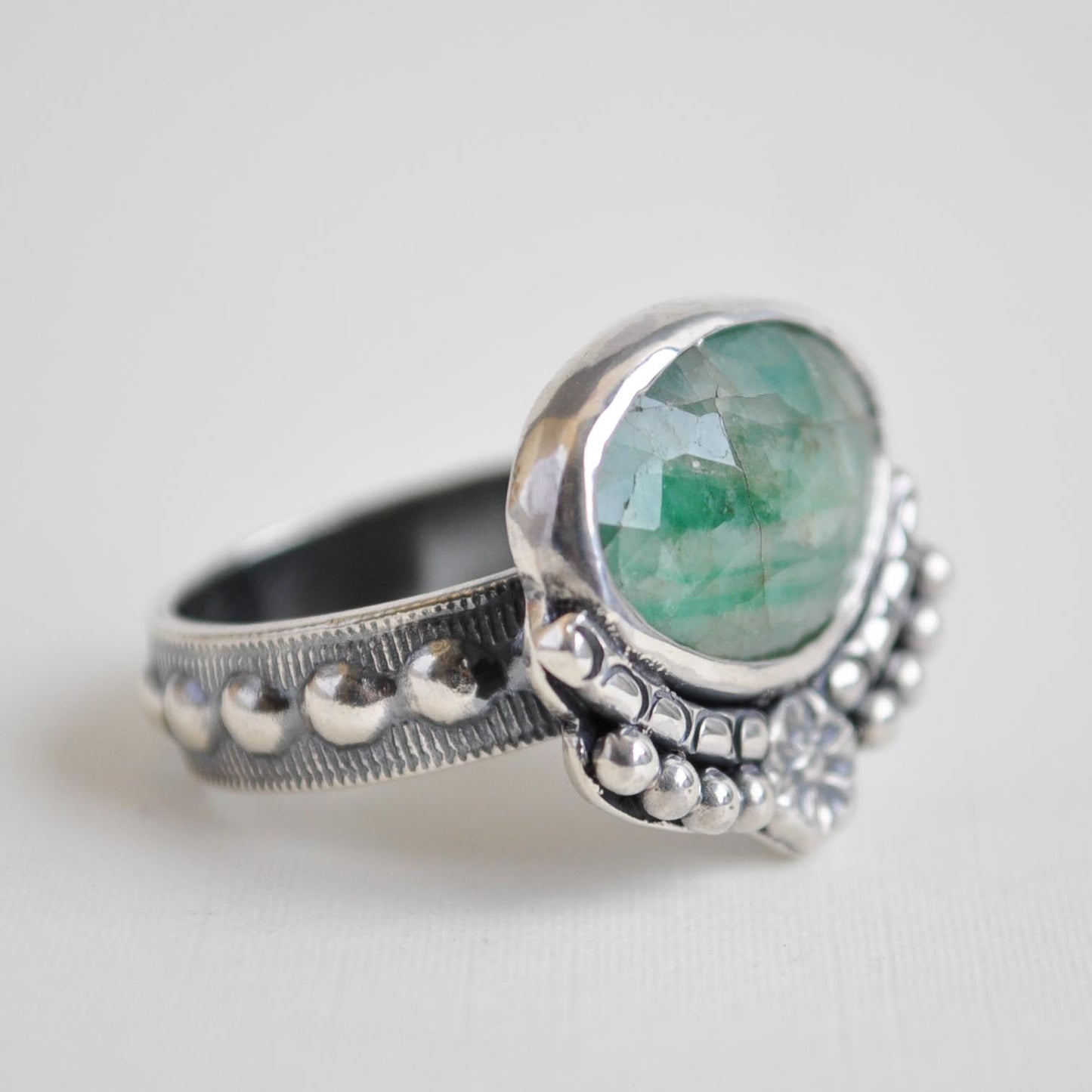 Silver ring with a green gemstone on a white background