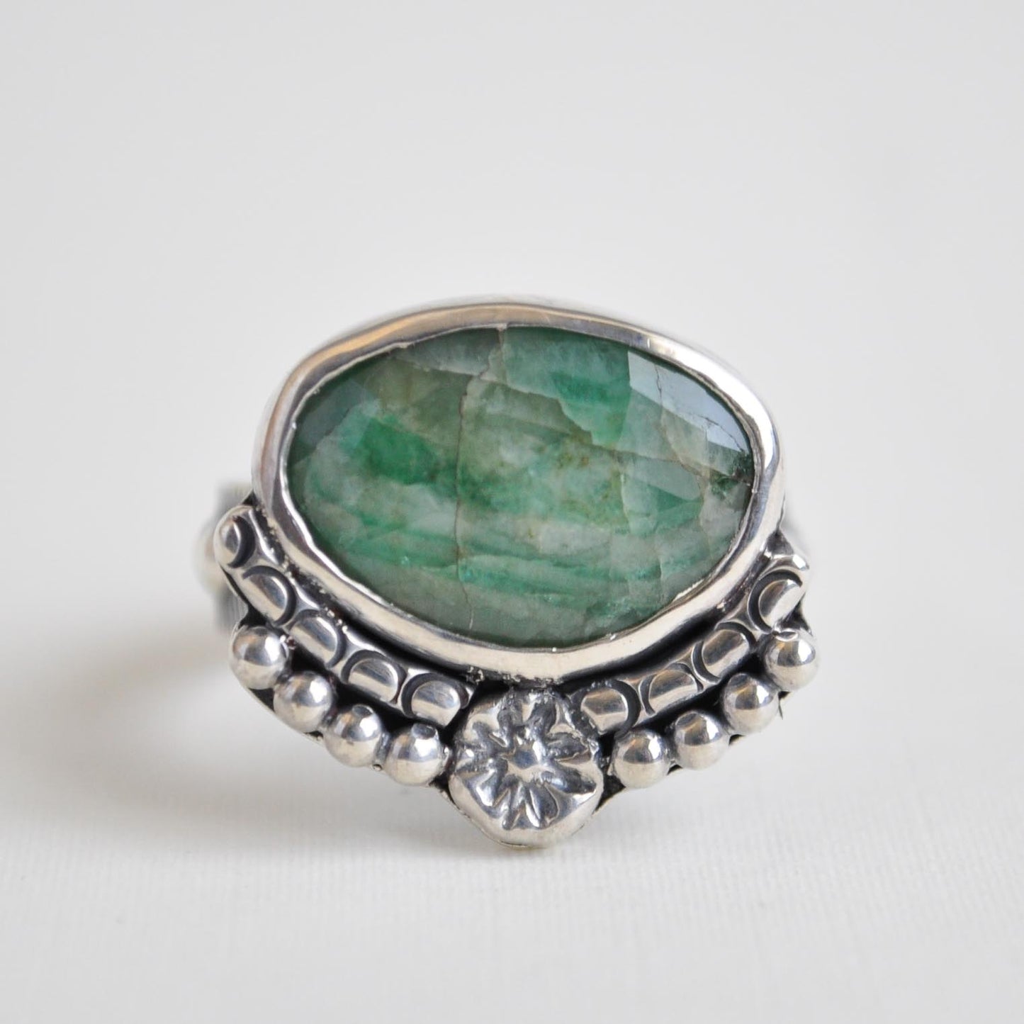 Silver ring with a green gemstone on a white background