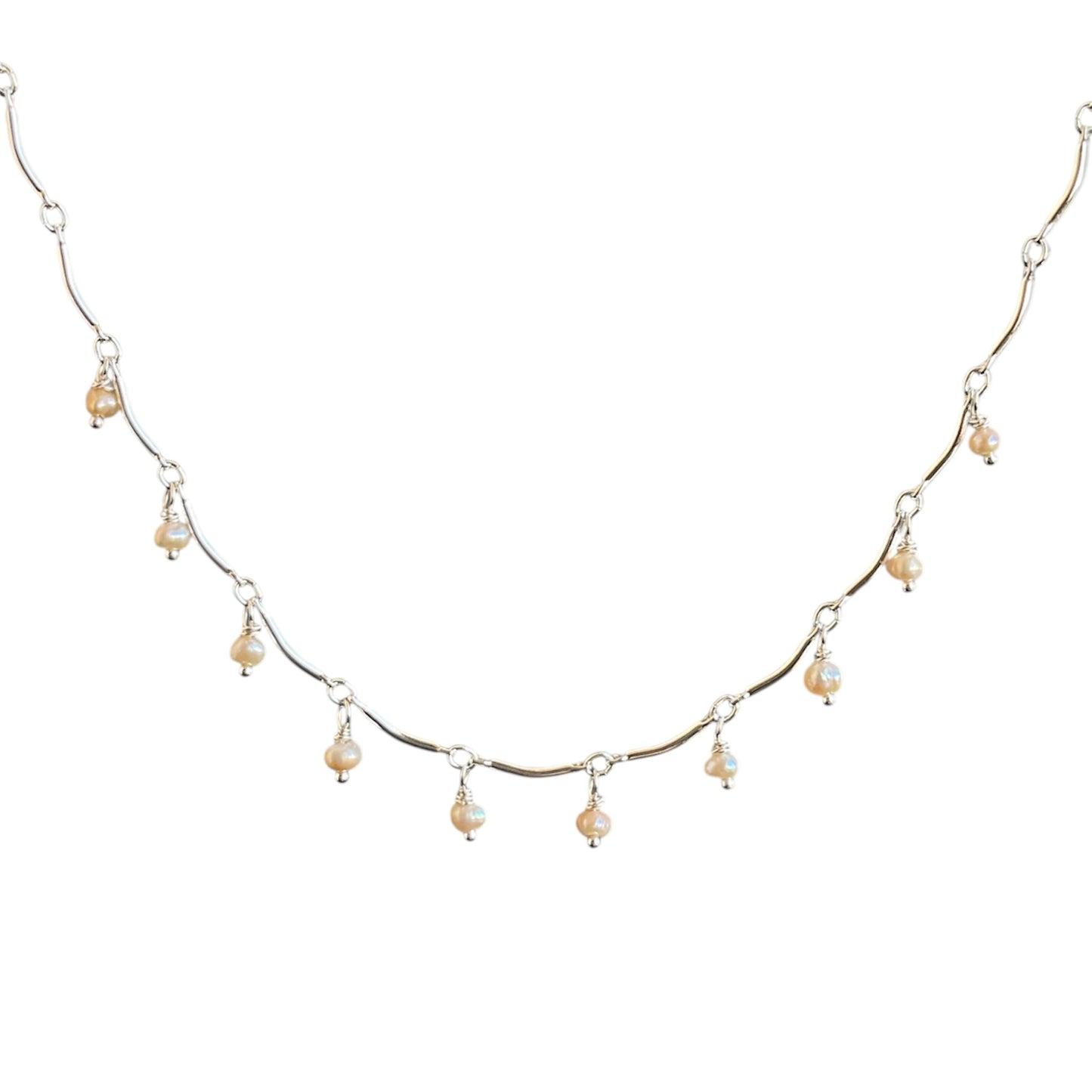 Delicate silver necklace with small pearls on a white background