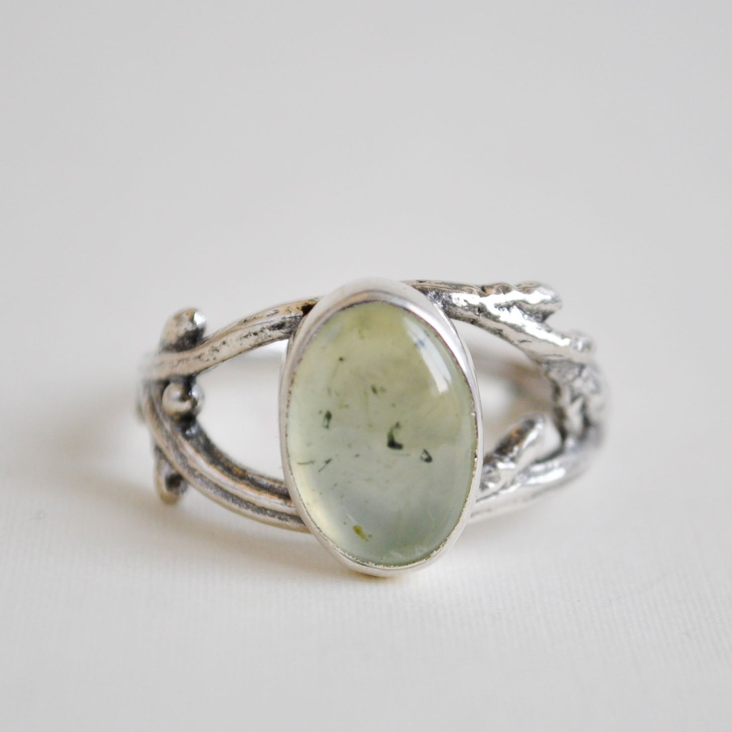 Silver ring with a green stone on a light gray background