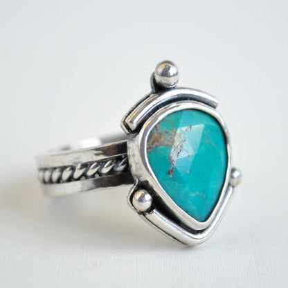 Silver ring with a turquoise stone on a white background