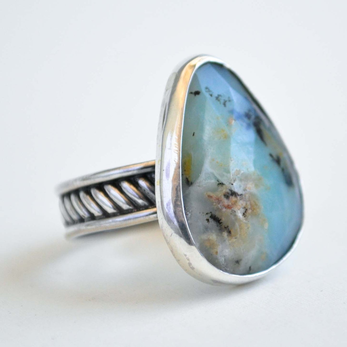 Silver ring with a large, tear drop-shaped stone on a white background