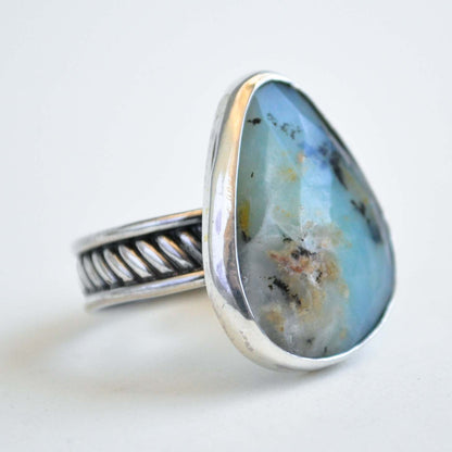 Silver ring with a large, tear drop-shaped stone on a white background