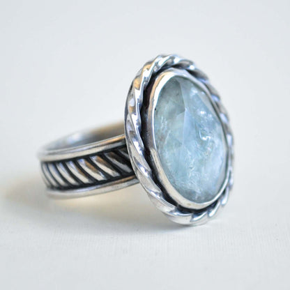 Silver ring with a light blue stone on a white background