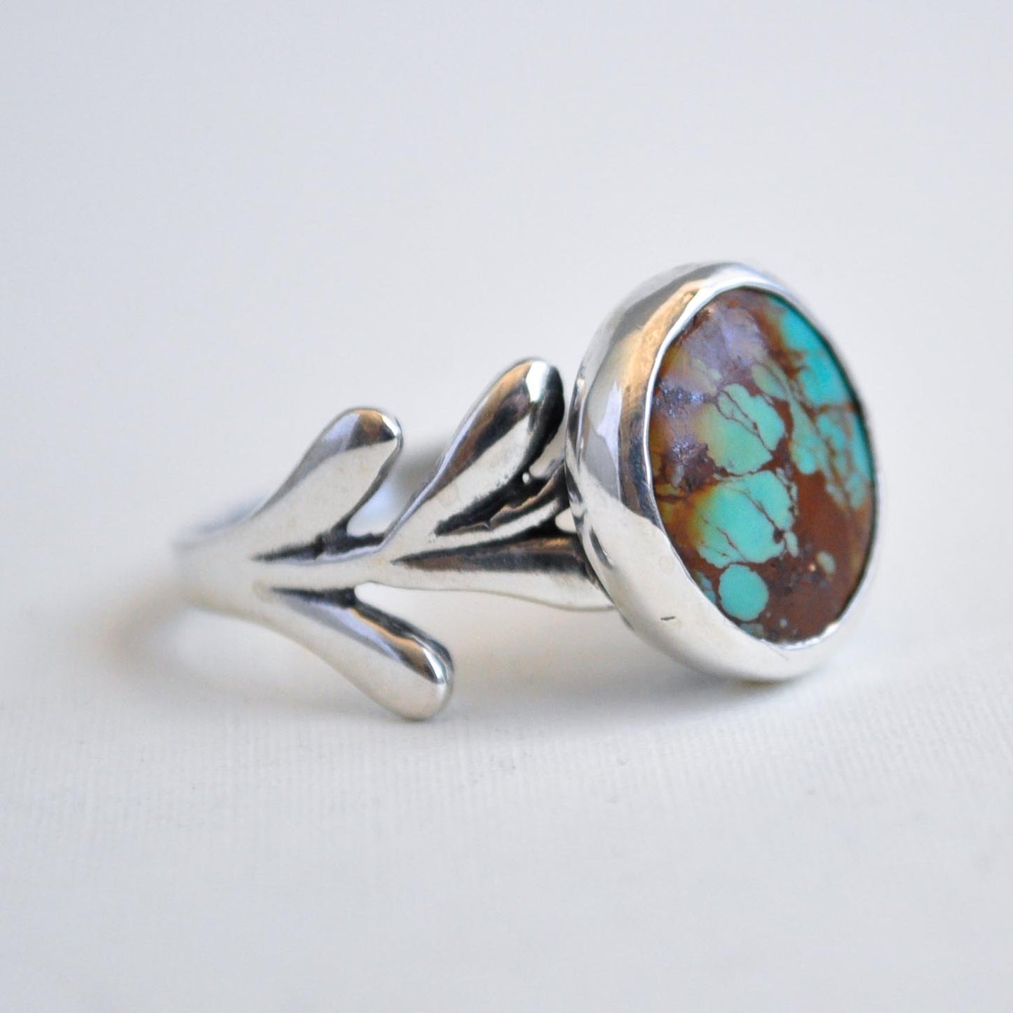 Silver ring with a colorful stone on a light gray background