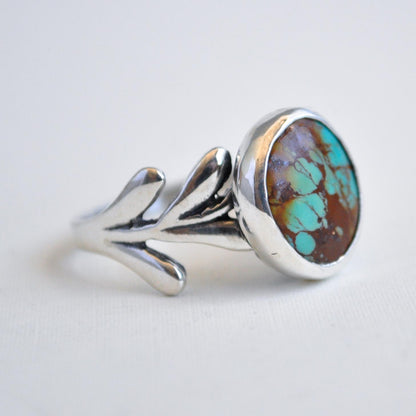 Silver ring with a colorful stone on a light gray background