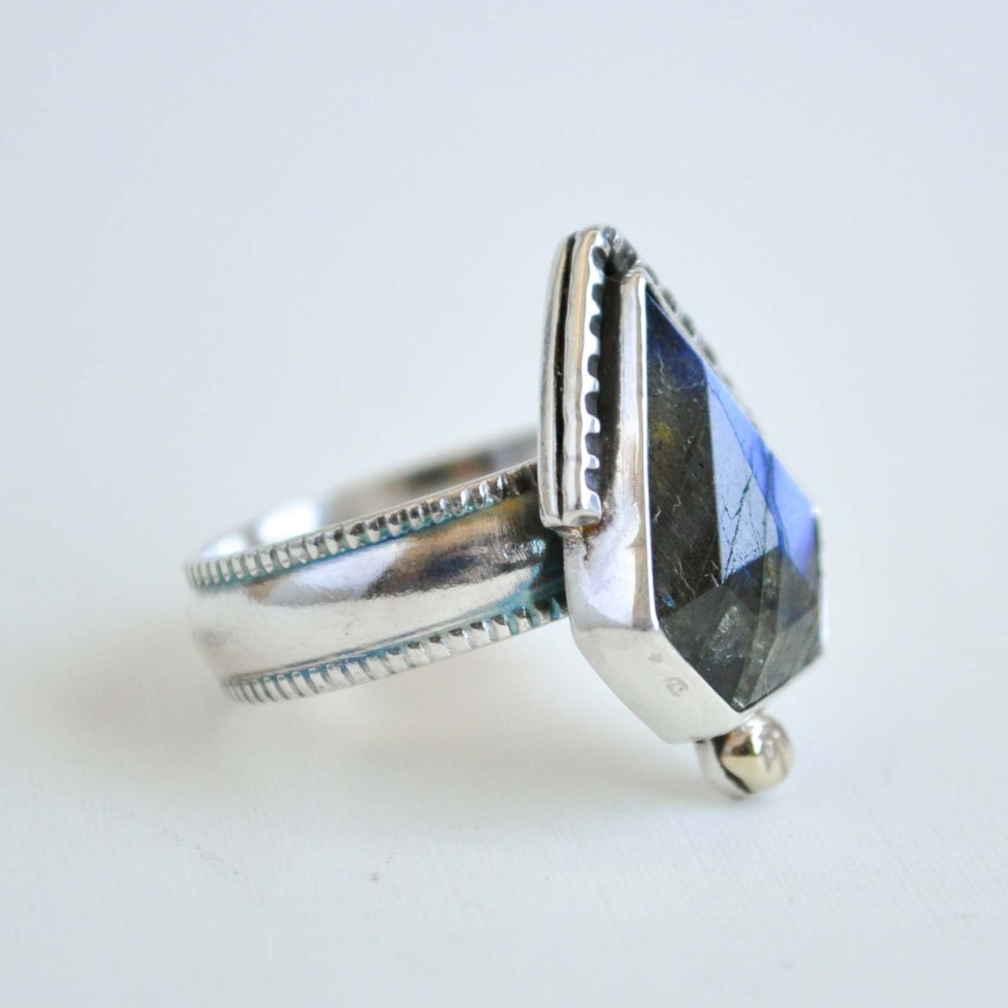 Silver ring with a large, faceted gemstone on a light background