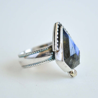 Silver ring with a large, faceted gemstone on a light background