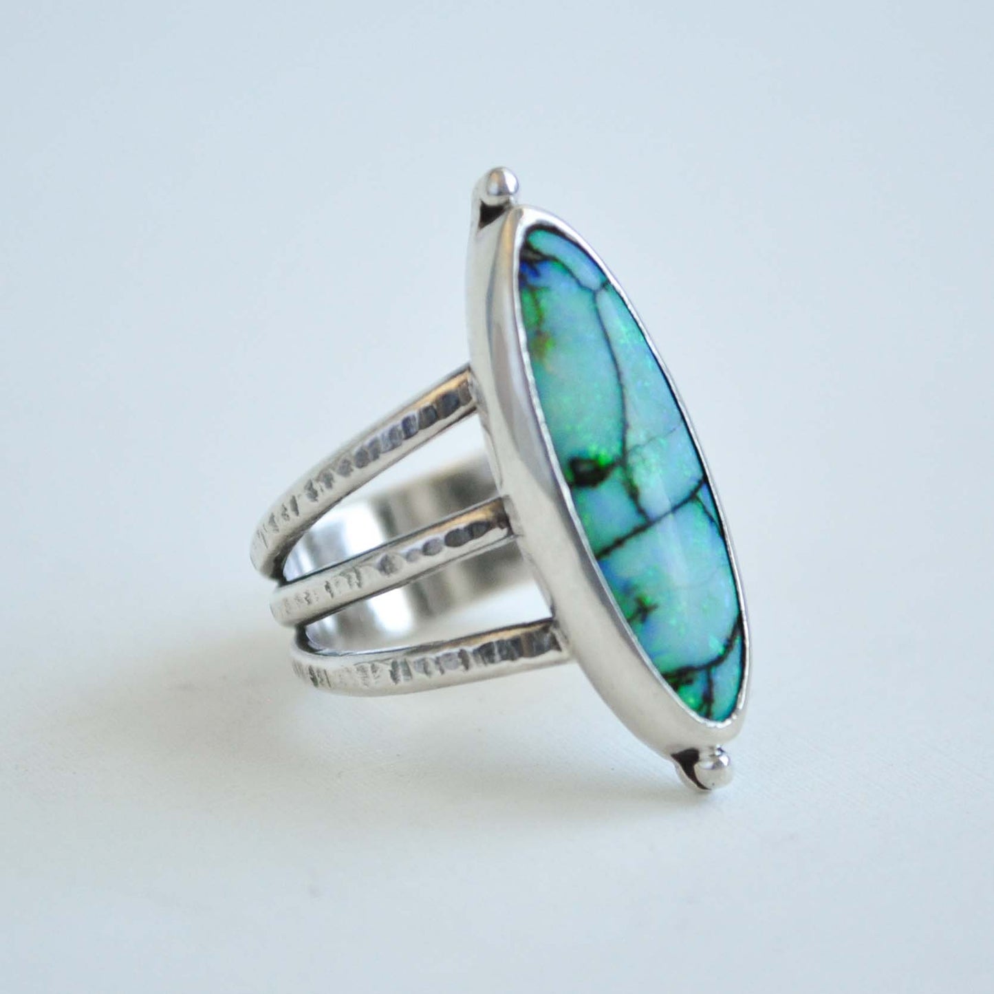 Silver ring with a blue opal stone on a light gray background