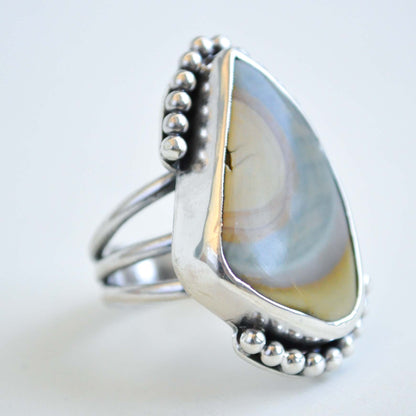 Silver ring with a teardrop-shaped stone on a light gray background