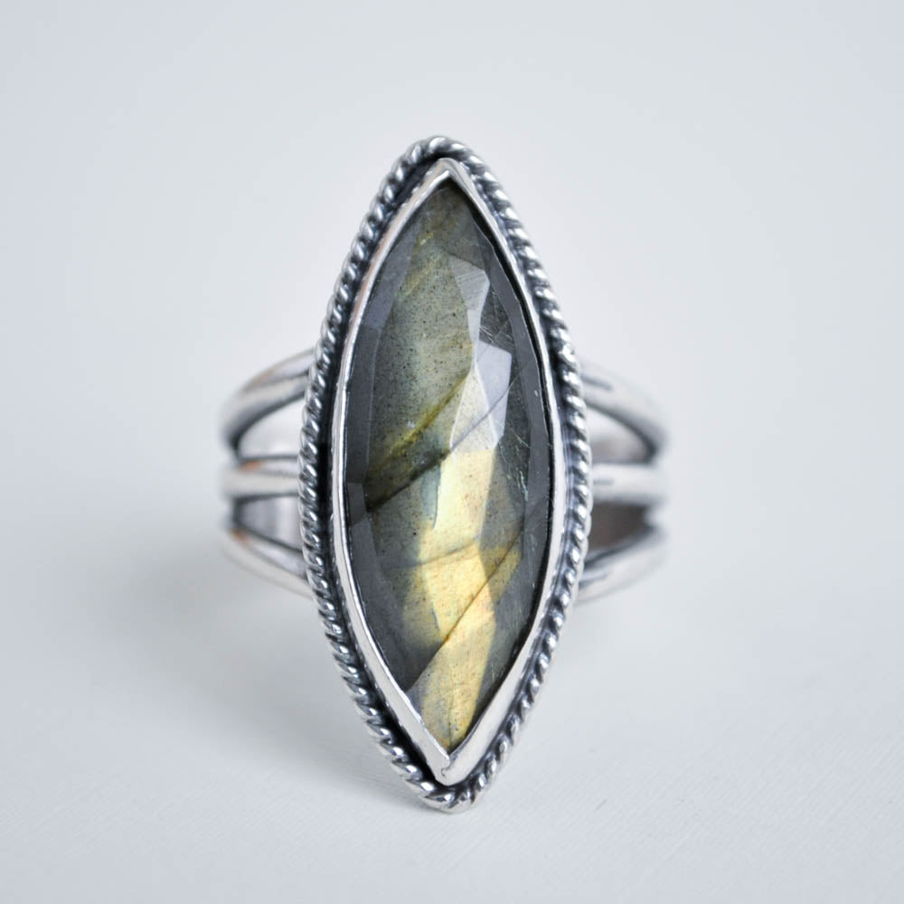 Long marquise shaped labradorite gemstone with a twisted border on a split trio ring band. 