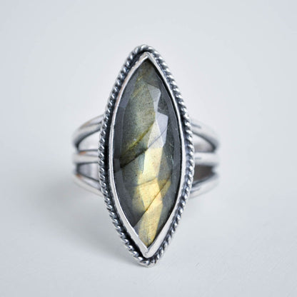 Long marquise shaped labradorite gemstone with a twisted border on a split trio ring band. 