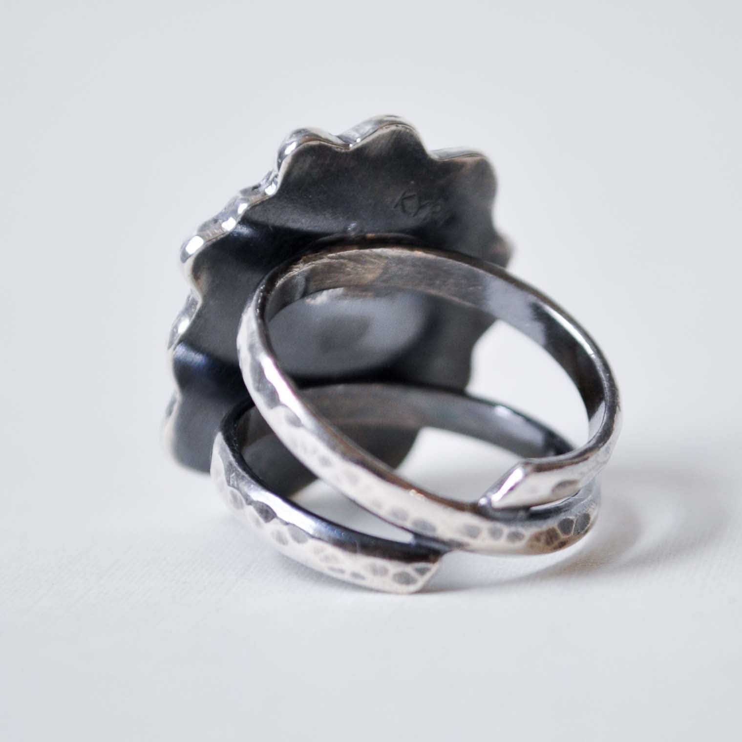 Silver ring with textured design on a white background