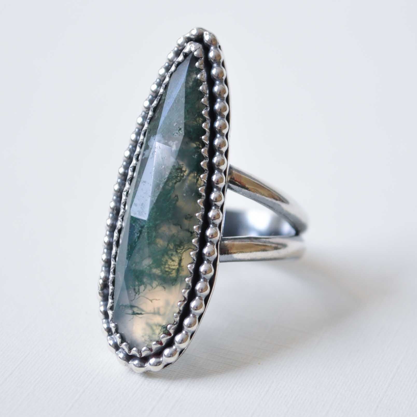 Silver ring with a large, faceted gemstone on a white background