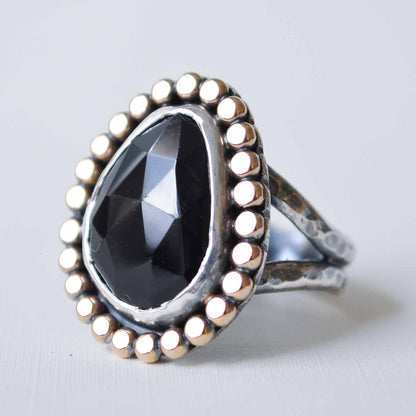 Silver ring with a large black gemstone on a light gray background