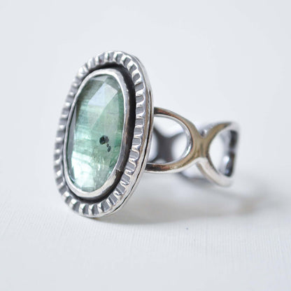 Silver ring with a green gemstone on a white background