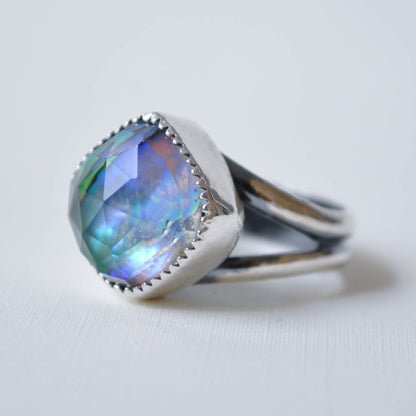 Silver ring with a colorful gemstone on a light gray background