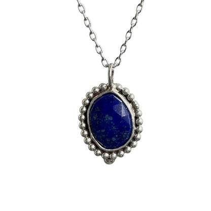 Silver pendant with a blue stone on a white background