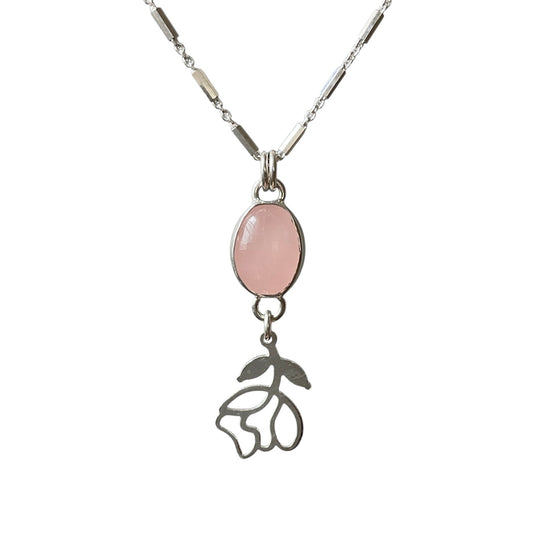 Necklace with a pink stone pendant and floral charm on a white background