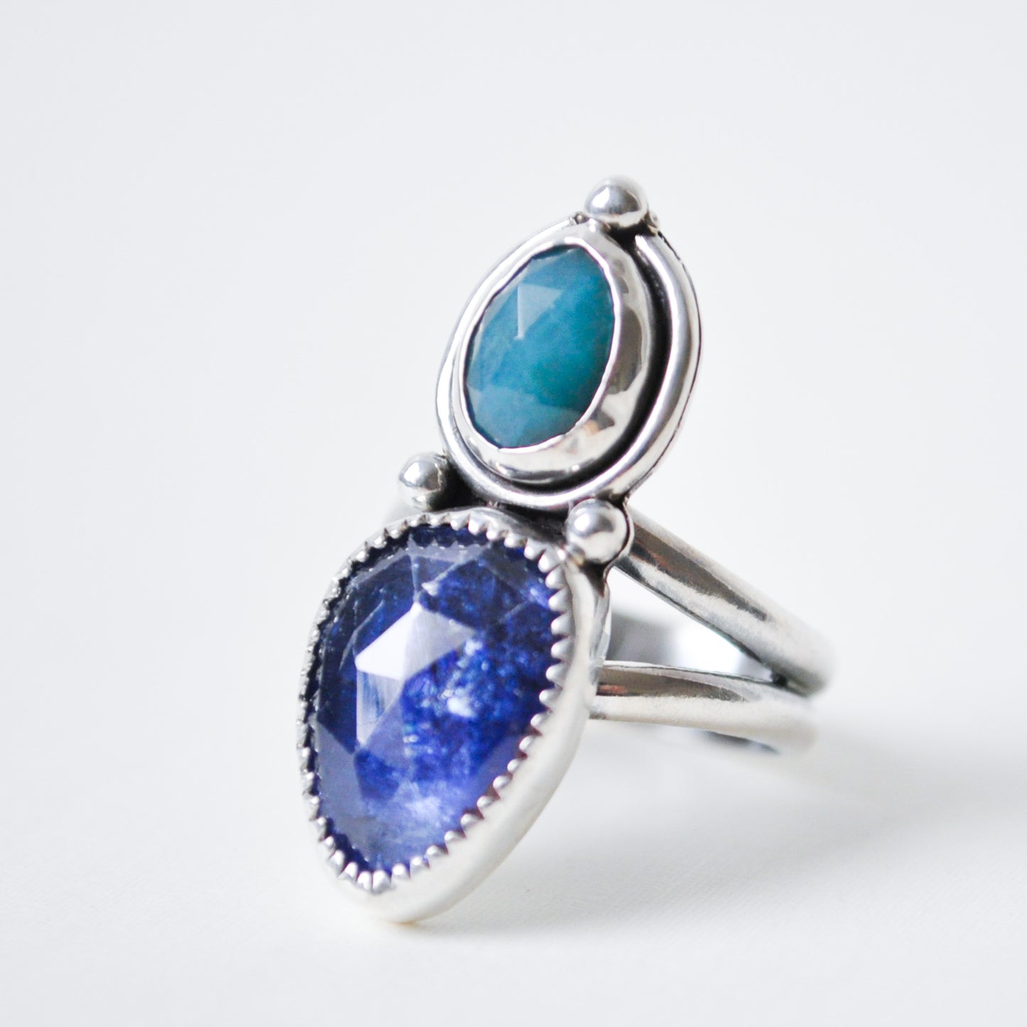 Silver ring with blue and green gemstones on a white background