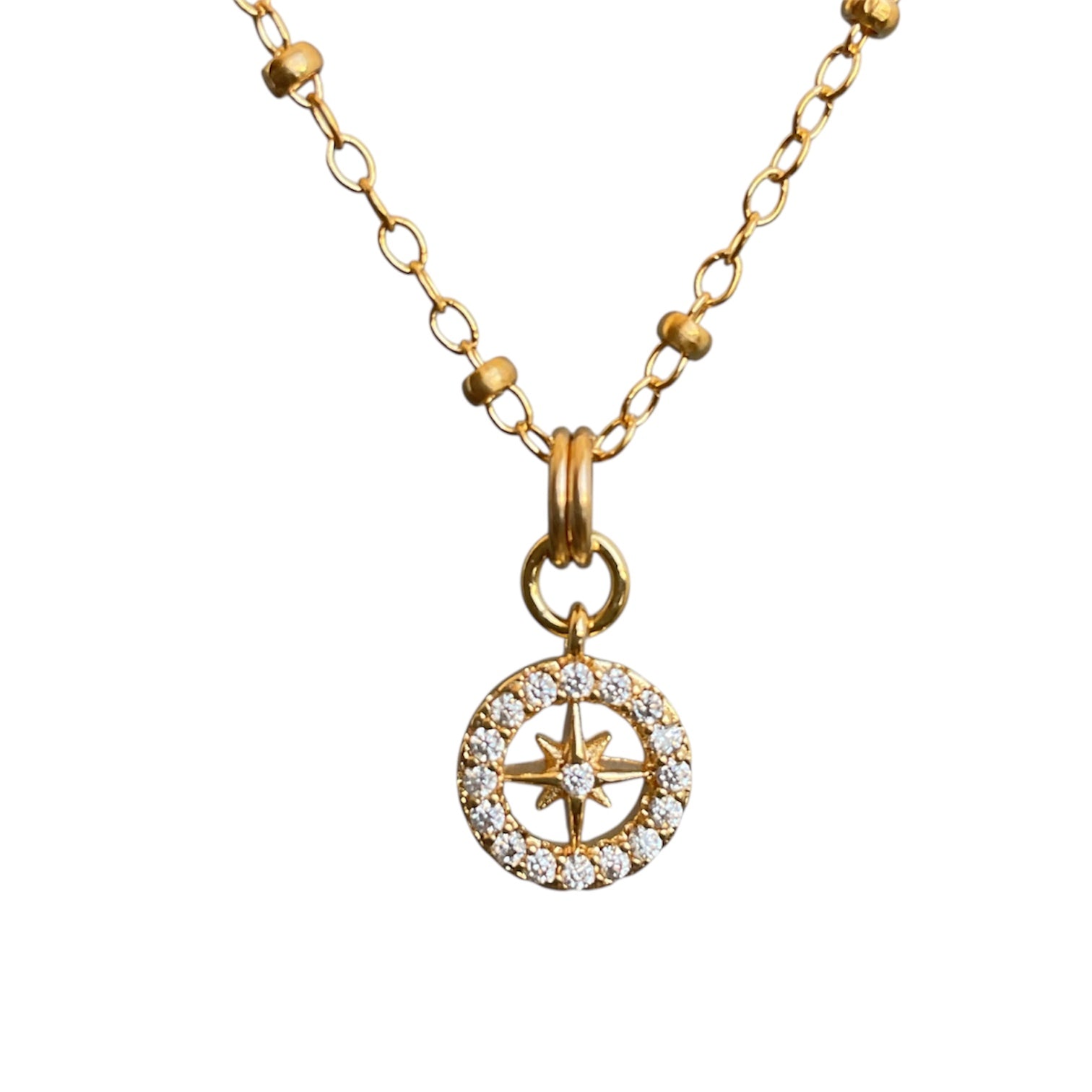 Gold compass necklace with a star-shaped pendant on a white background