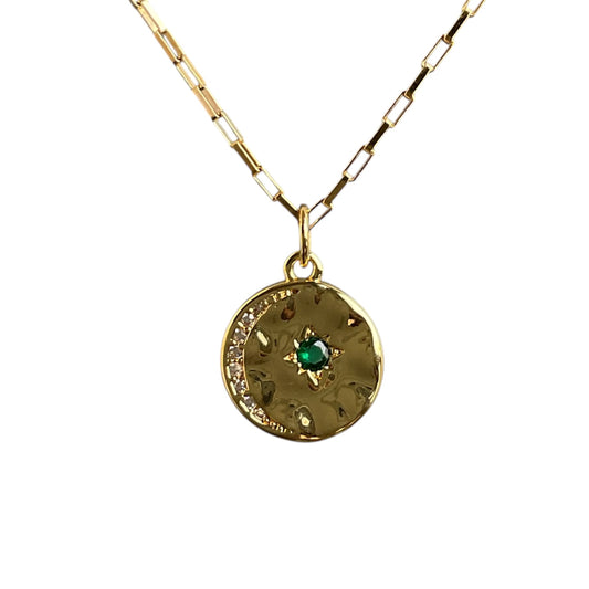Gold necklace with a pendant featuring a green gemstone on a white background