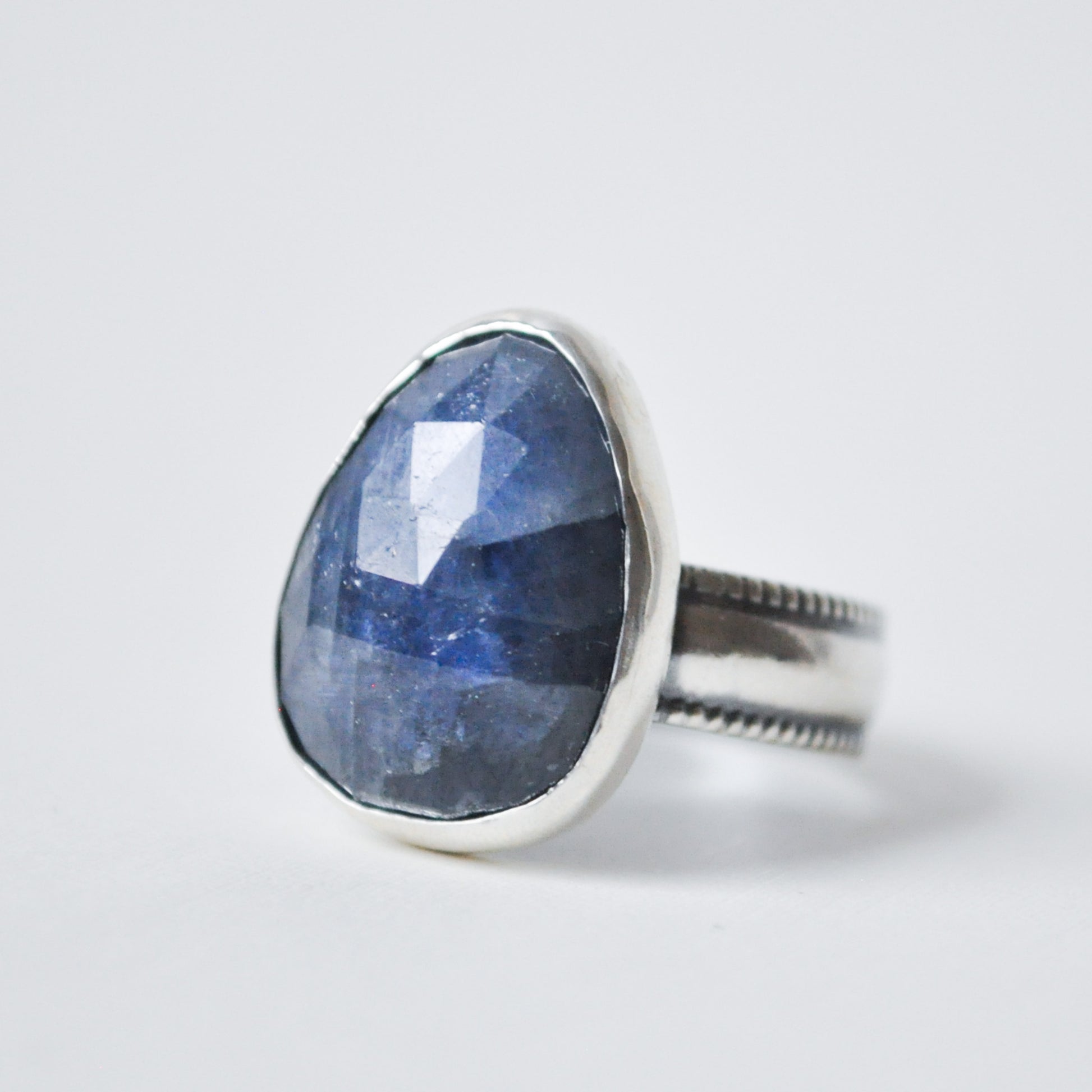 Silver ring with a large blue stone on a white background