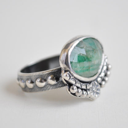 Silver ring with a green gemstone on a white background