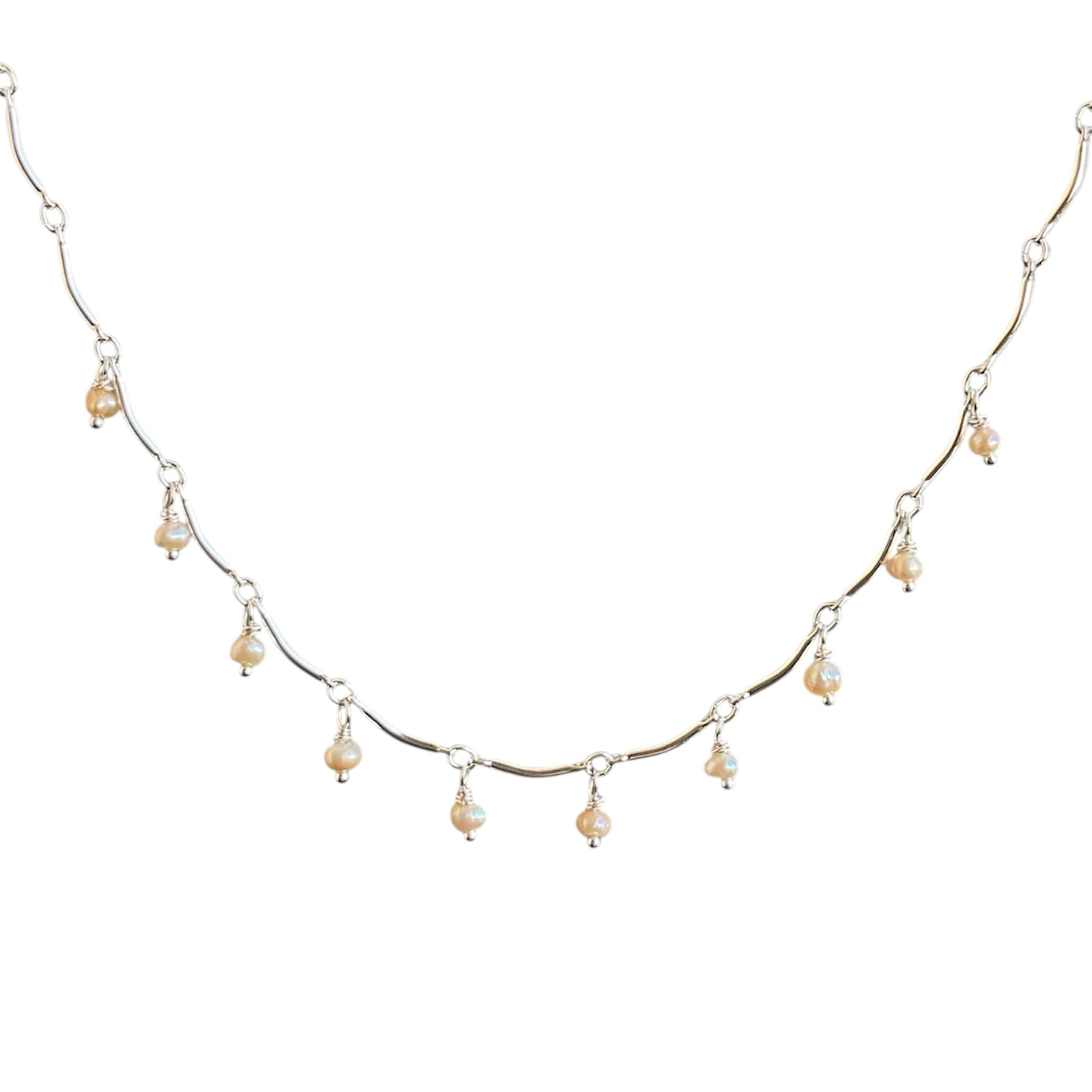 Delicate silver necklace with small pearls on a white background