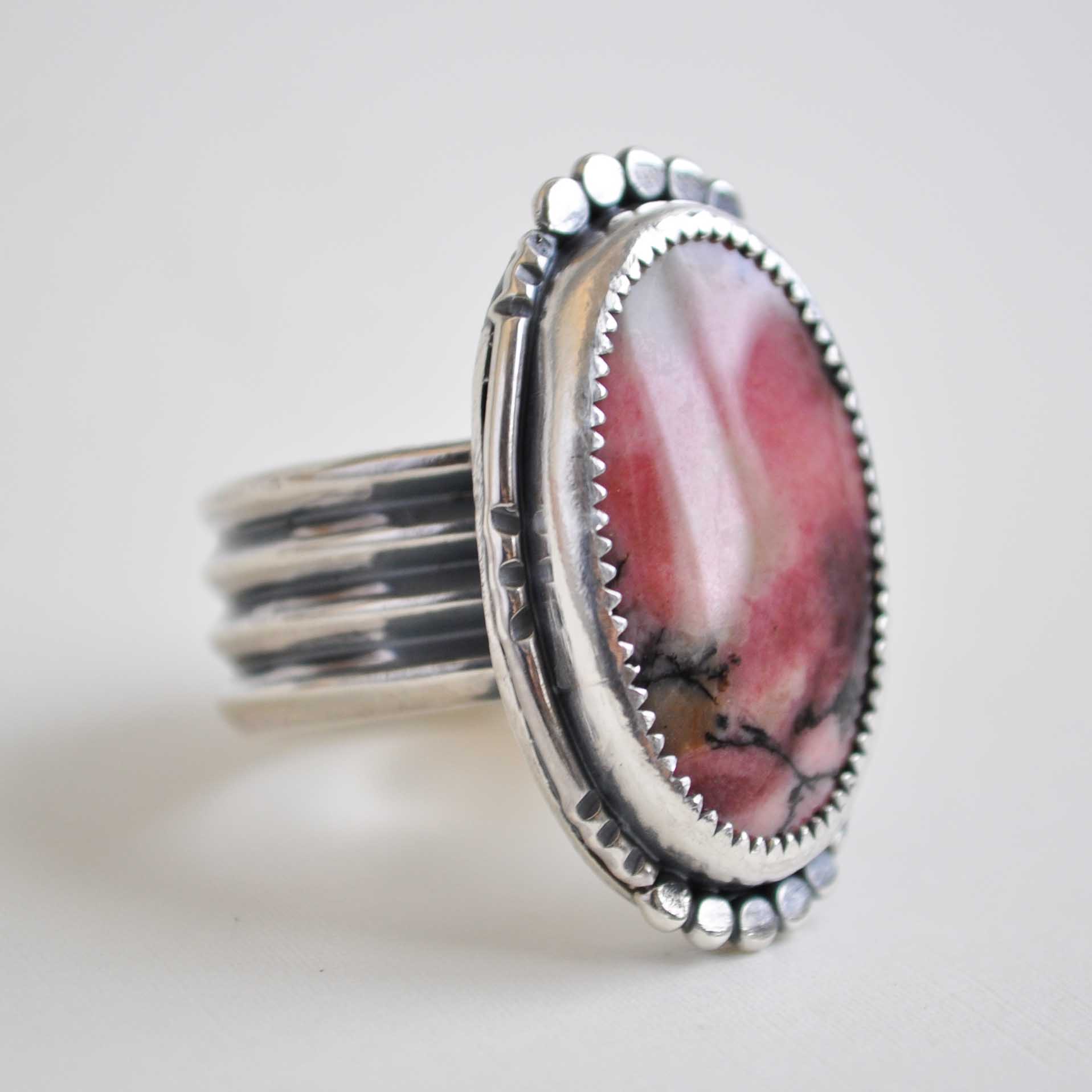 Silver ring with a pink stone on a light gray background