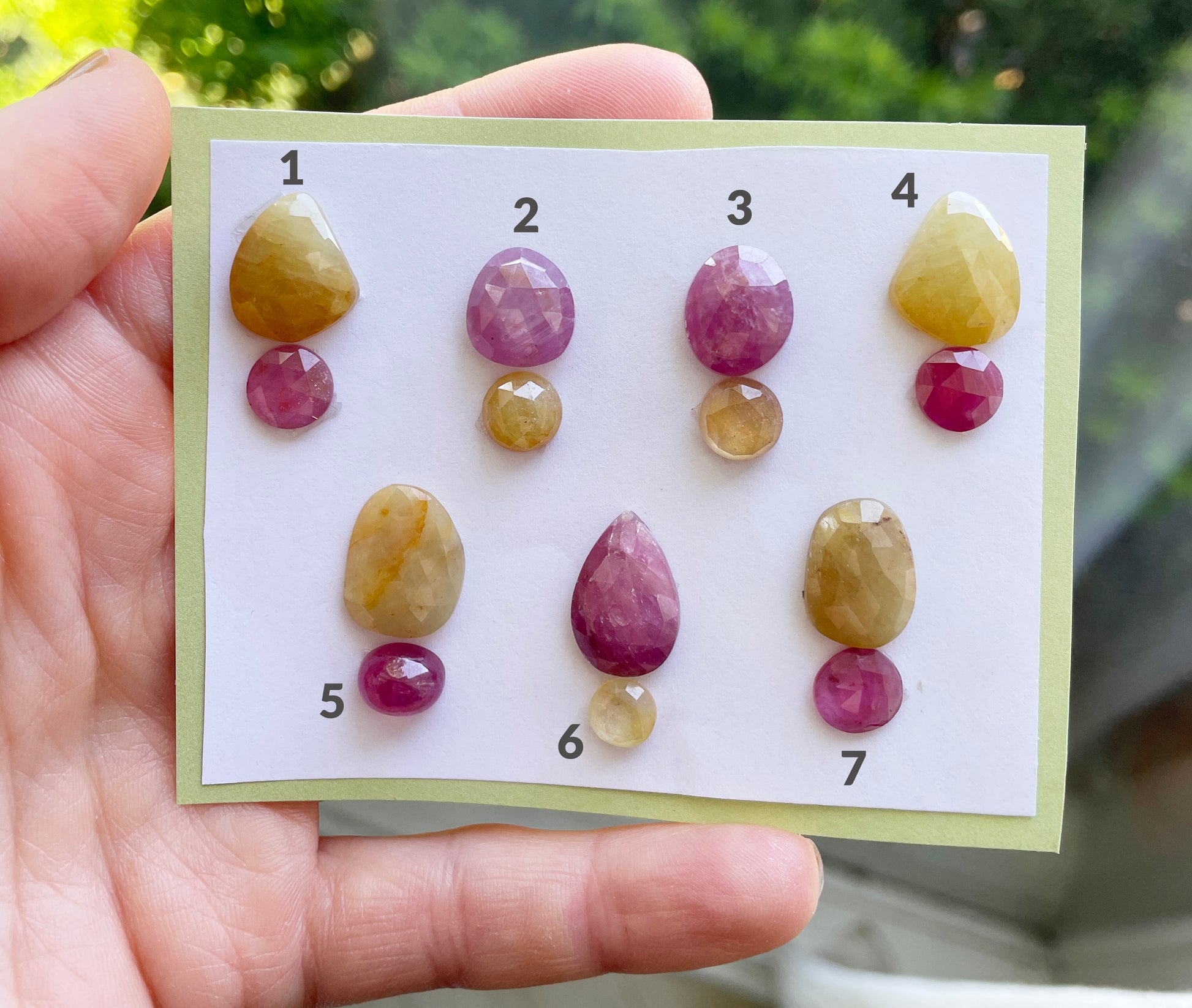 Hand holding a card with colored gemstones arranged in rows.
