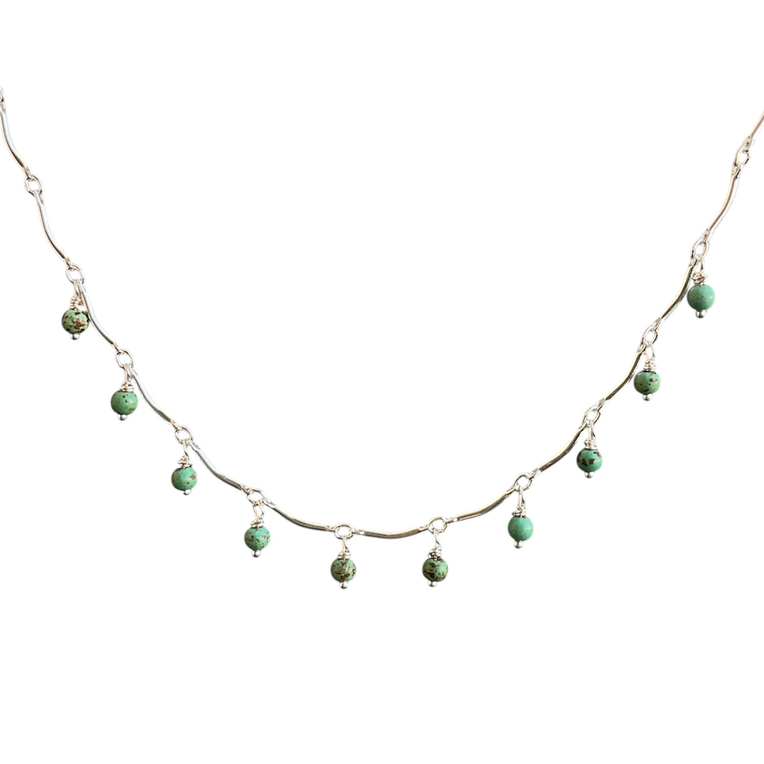 Scalloped silver necklace with green beads on a white background